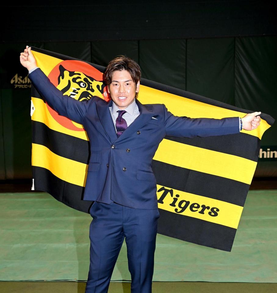 　球団旗を手にポーズを決める梅野（撮影・飯室逸平）