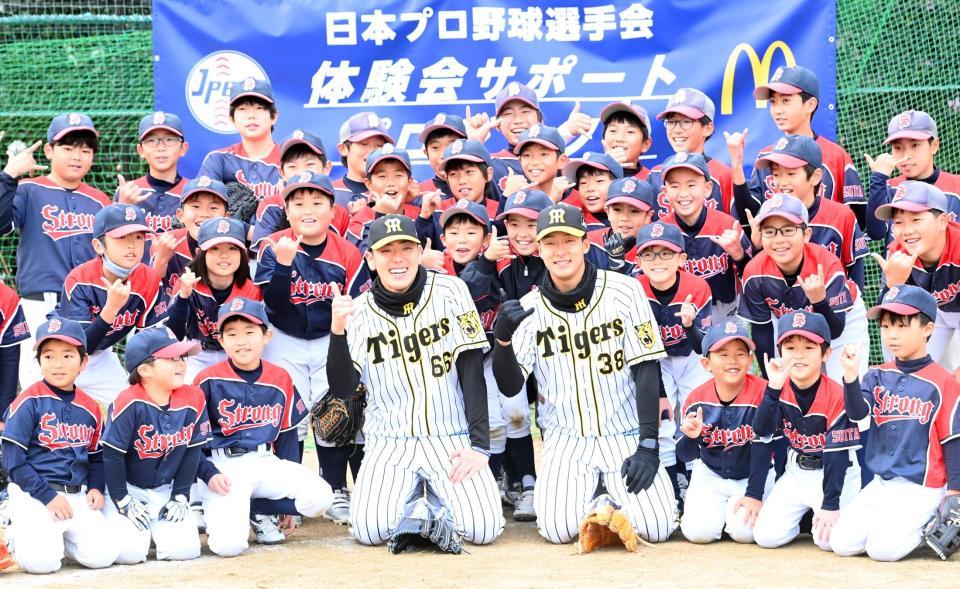子どもたちと笑顔で記念写真におさまる阪神・小川一平（中央左）と阪神・小幡竜平＝吹田市・佐竹台小学校（撮影・飯室逸平）