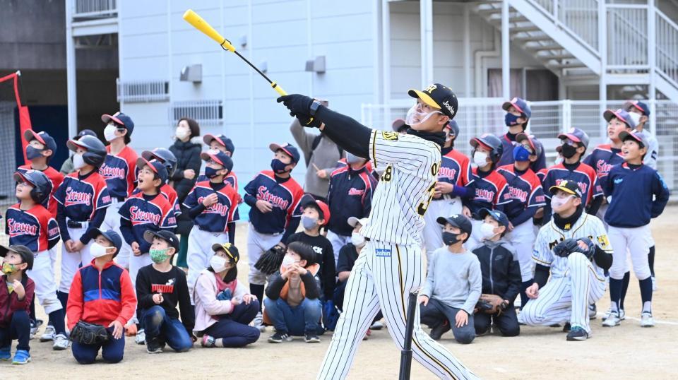 子どもたちの前で豪快なバッティングを披露する阪神・小幡竜平＝大阪・吹田市佐竹台小学校（撮影・飯室逸平）