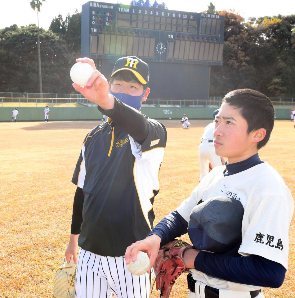 ボールの握りを見せながらアドバイスする阪神・高橋遥人＝鹿児島・ビーラインスポーツパーク姶良　野球場（撮影・田中太一）