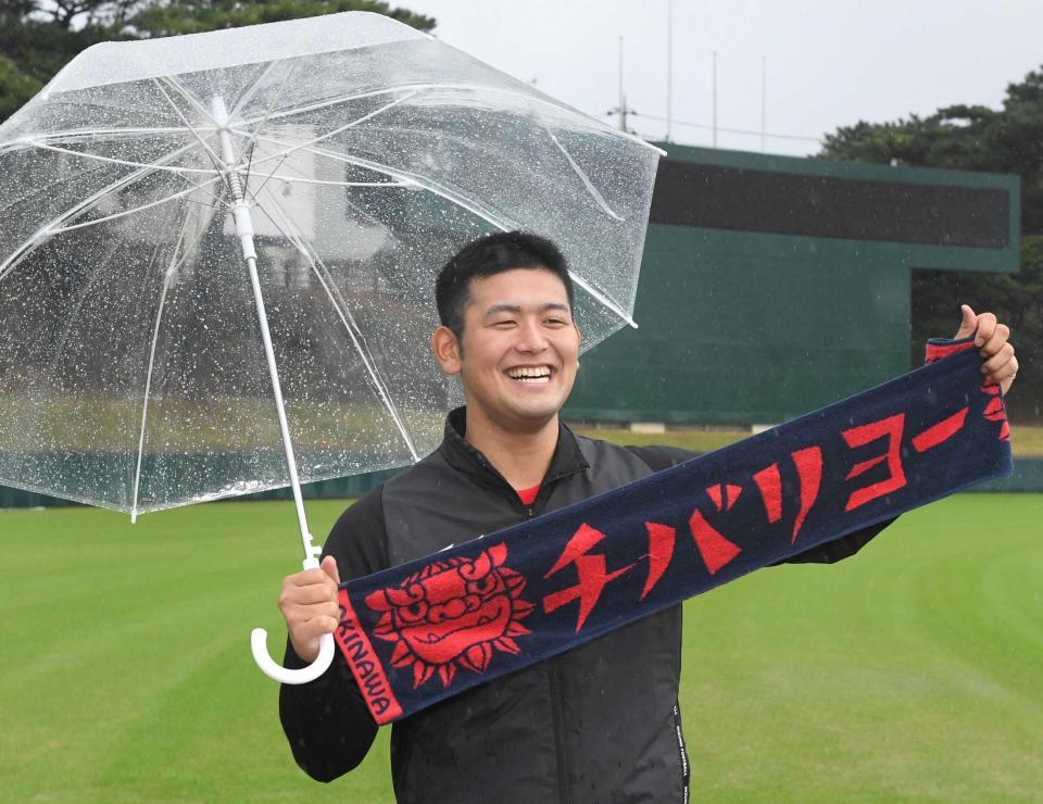 　「チバリヨー！（頑張れ！）」。雨が降る中、傘を差しながら笑顔を見せる岡留（撮影・田中太一）　