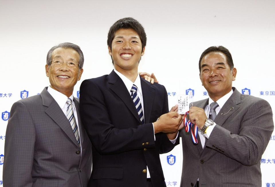 　ドラフト４位指名のあいさつを受け、笑顔の東京国際大・伊藤和。左は古葉監督＝１１年１１月４日