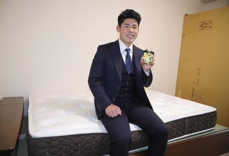 入寮し、マットレスの上で笑顔を見せる鈴木（球団提供）