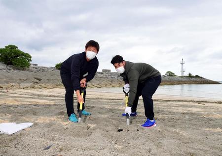 　ビーチの軽石を除去する桐敷（左）と鈴木（撮影・山口登）