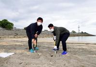 　ビーチの軽石を除去する桐敷（左）と鈴木（撮影・山口登）