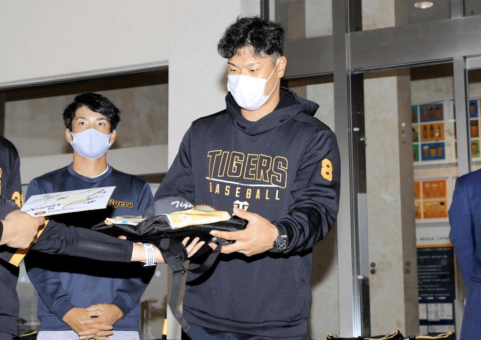 　こども医療センターに訪問し、タイガースグッズを病院の関係者に渡す佐藤輝（右）。左は高寺（代表撮影）