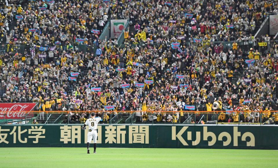 　６回守備に就く佐藤輝は、歓喜するファンに手を挙げて応える（撮影・山口登）