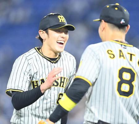 　７回、ピンチをしのぎ、笑顔で佐藤輝とタッチを交わす小川（撮影・飯室逸平）