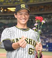 カーネーションを手にポーズを決める湯浅（撮影・飯室逸平）