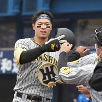 ３回、８号ソロを放ちメダルを胸にタッチを交わす阪神・佐藤輝明＝横浜スタジアム（撮影・飯室逸平）