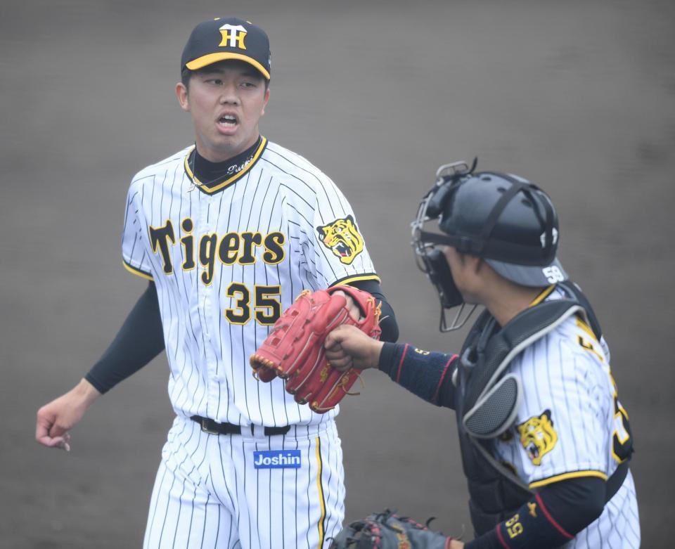 　７回、好投を見せ、藤田とタッチをかわしベンチに戻る才木（左）＝撮影・石井剣太郎