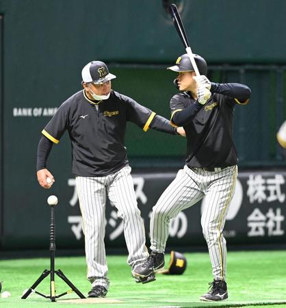 　藤井康コーチ（左）から打撃のアドバイスを受ける佐藤輝（撮影・飯室逸平）