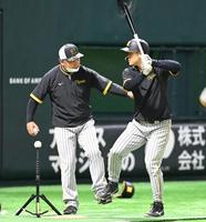 　藤井康コーチ（左）から打撃のアドバイスを受ける佐藤輝（撮影・飯室逸平）