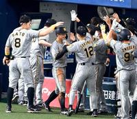 　生還を果たし、佐藤輝（左端）らナインに迎えられる（中央）