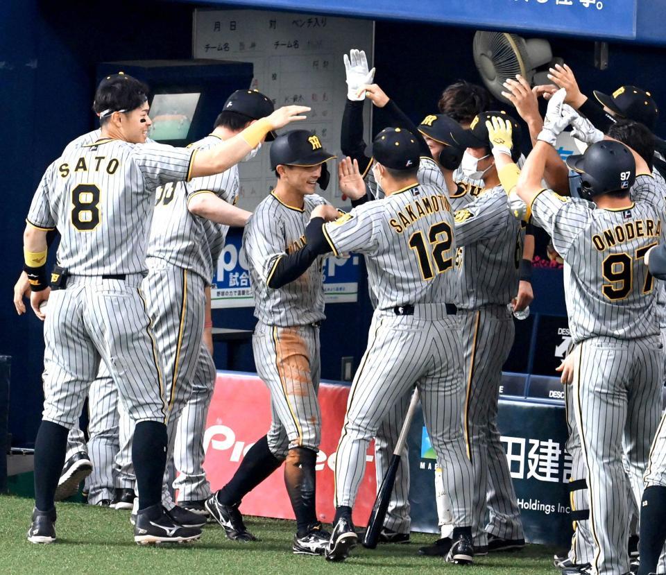 　生還を果たし、佐藤輝（左端）らナインに迎えられる（中央）