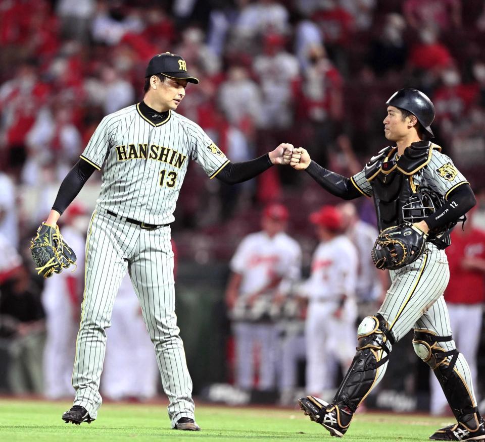 　延長１２回、ピンチをしのぎ、坂本（右）とタッチを交わす岩崎（撮影・飯室逸平）