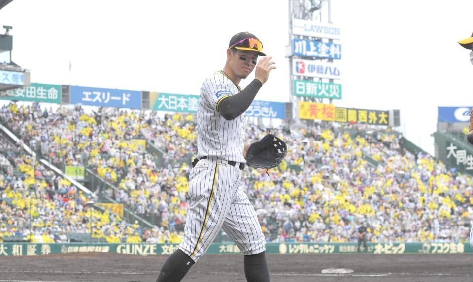 　７回の守備に向かう際、スタンドからの声援に右手を挙げて応える佐藤輝（撮影・北村雅宏）