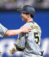 　３回、２８試合連続安打となる左前打を放ち塁上で笑顔を見せる近本（撮影・飯室逸平）