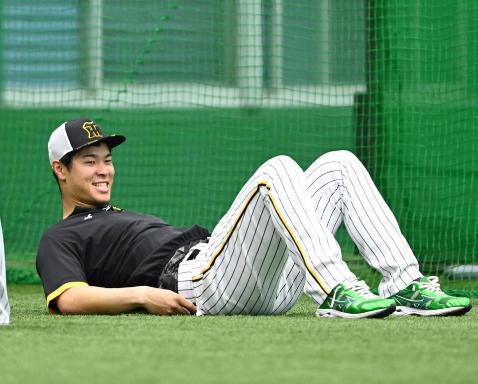 　ストレッチをしながら笑顔を見せる佐藤輝（撮影・田中太一）