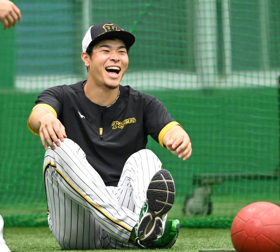 　練習前、ストレッチをしながら満面の笑みを浮かべる佐藤輝（撮影・田中太一）