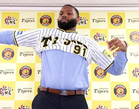 　阪神新入団会見でユニホームに袖を通すロドリゲス（代表撮影）