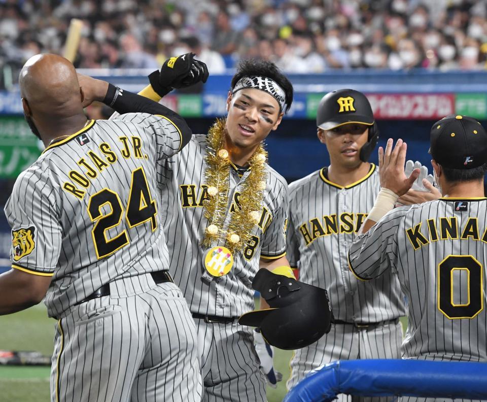 ６回、追撃の１７号２ランを放ち、タッチを交わす佐藤輝（中央）＝撮影・飯室逸平