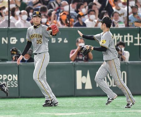 ６回、無失点に抑え、中野（右）とタッチを交わす才木＝東京ドーム（撮影・西岡正）