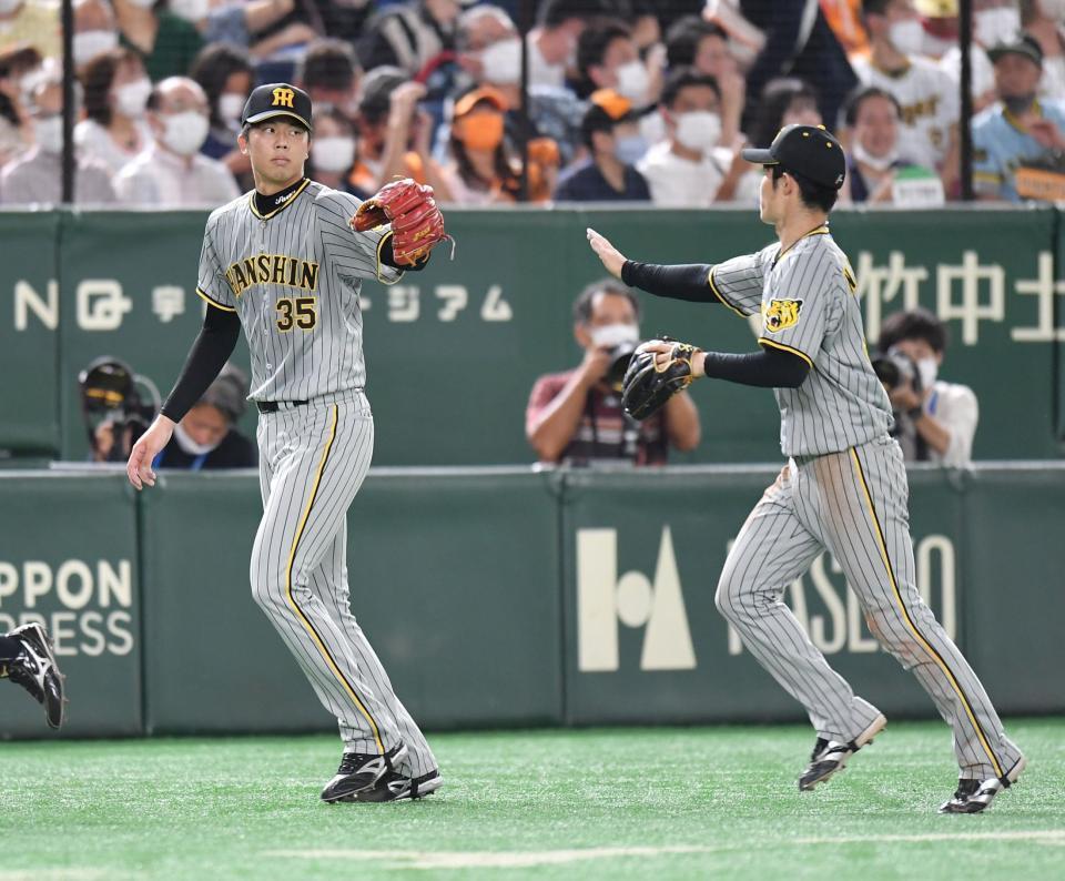 ６回、無失点に抑え、中野（右）とタッチを交わす才木＝東京ドーム（撮影・西岡正）