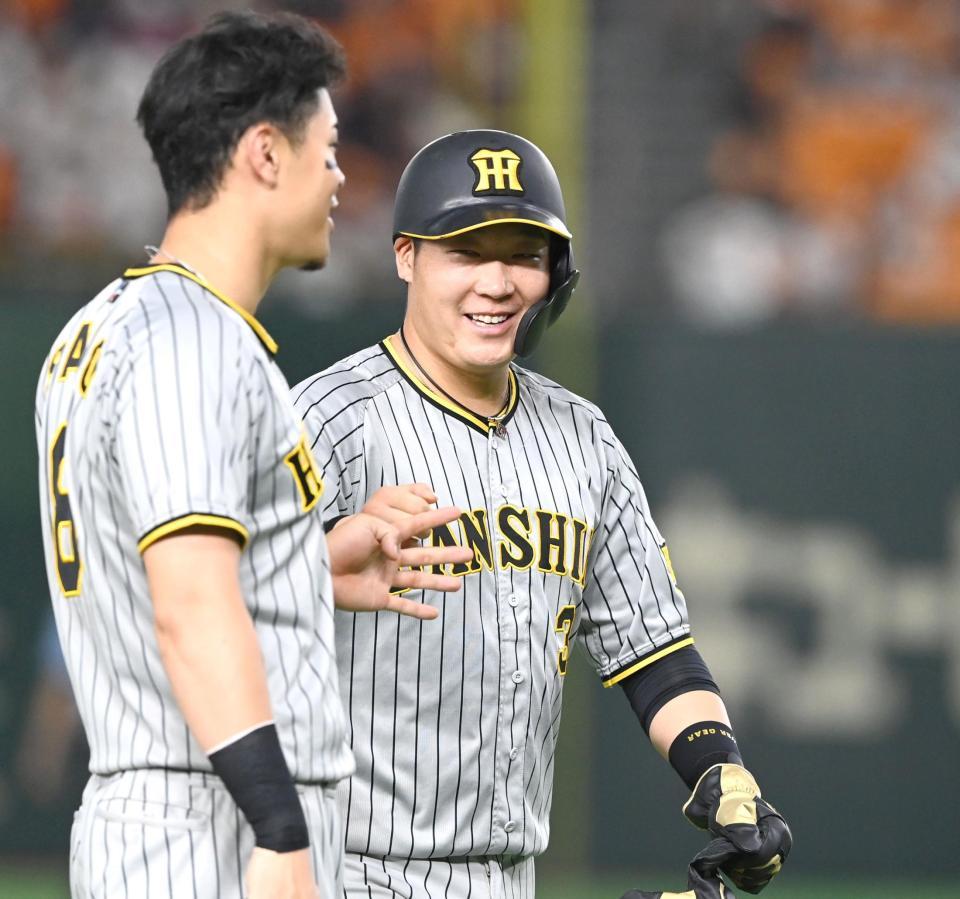 　８回、笑顔で佐藤輝（左）とタッチを交わす大山（撮影・飯室逸平）