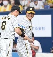 　２回、佐藤輝（左）とタッチをかわす西純（撮影・飯室逸平）