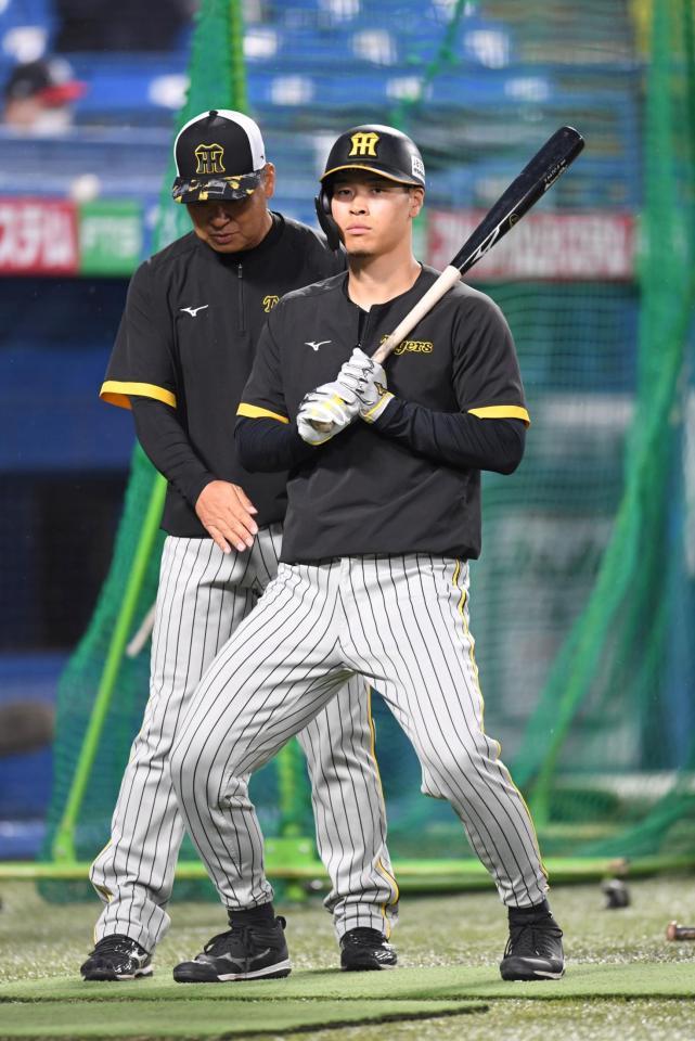 　藤井康コーチ（左）から打撃指導を受ける佐藤輝（撮影・棚橋慶太）