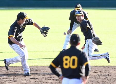 　二遊間ノックで渡辺（左）にグラブトスをする中野。手前は岡田監督（撮影・田中太一）