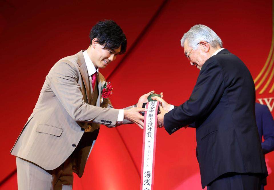 　セ最優秀中継ぎ投手賞に輝いた湯浅（左）は斉藤コミッショナーから笑顔でトロフィーを受け取る（代表撮影）