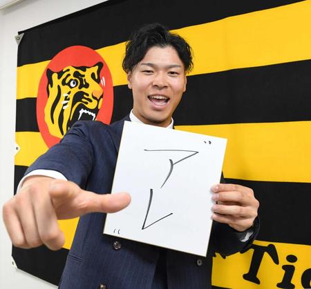 　「アレ」と記した色紙を手にポーズを決める佐藤輝（撮影・飯室逸平）