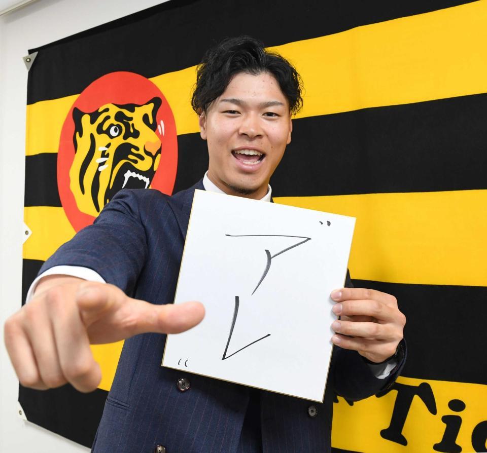 　「アレ」と記した色紙を手にポーズを決める佐藤輝（撮影・飯室逸平）