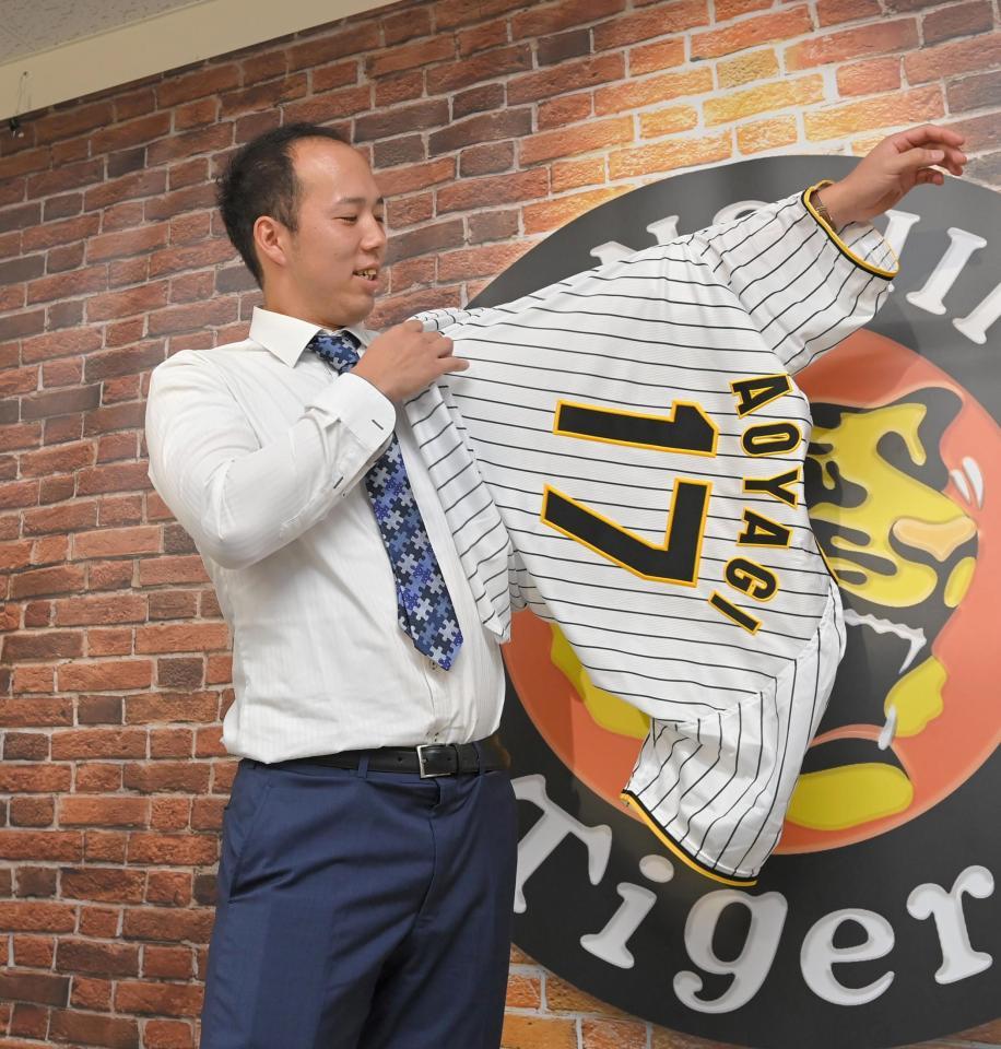 　「１７」のユニホームに袖を通す青柳（撮影・高部洋祐）