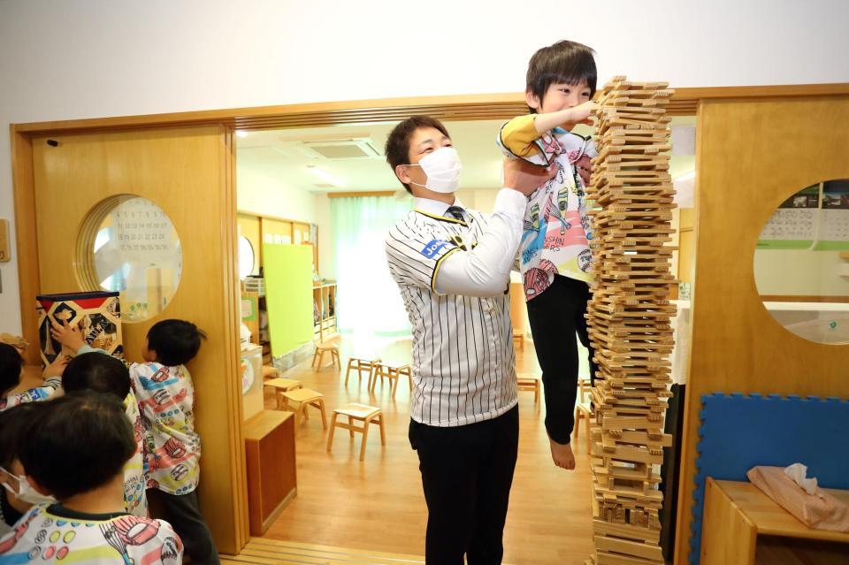 　寄贈した玩具で園児と遊ぶ岩崎＝西宮市立浜甲子園保育所（球団提供）