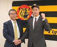 　入団会見を終え、嶌村球団本部長（左）に帽子をかぶせてもらう大竹（撮影・高部洋祐）