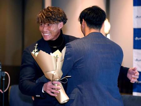 　佐藤輝（右）から花束を受け取り、笑顔を見せる糸井氏（撮影・田中太一）