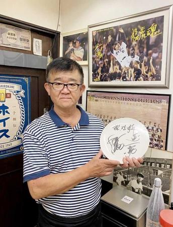 　岡田監督の直筆サインが入った開店３５周年の記念品を手に持つ阪神ＯＢ・中谷賢平さん