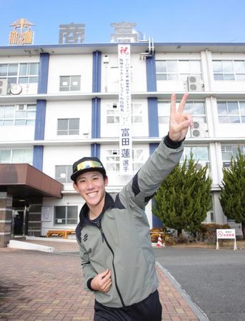 　母校に掲げられた幕の前でポーズを決める富田（撮影・坂部計介）
