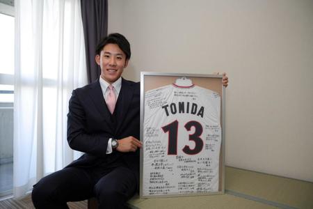 　入寮し自室で笑顔の富田（球団提供）