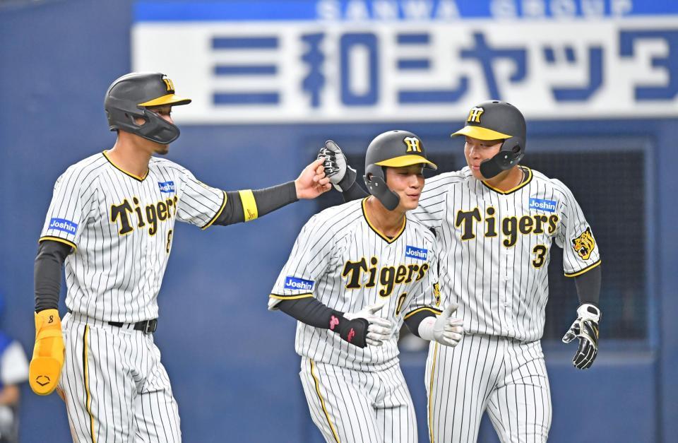 　７回、糸原の適時打で生還した二走・佐藤輝（左）と三走・大山はタッチを交わす。中央は木浪（撮影・中田匡峻）