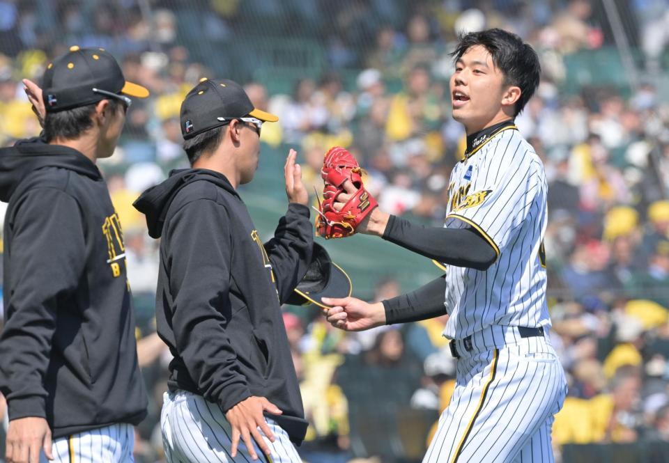 　１回を三者三振で終えてナインとタッチを交わす才木（撮影・立川洋一郎）