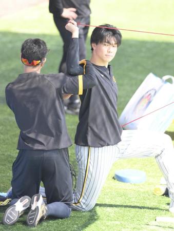 　トレーナーと共に右肩のストレッチを行う湯浅（撮影・伊藤笙子）