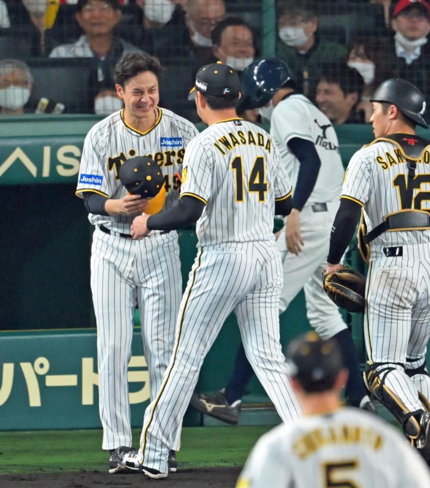 ７回、リリーフして後続を断った岩貞（１４）を安堵（あんど）の表情を浮かべて迎える大竹（撮影・立川洋一郎）