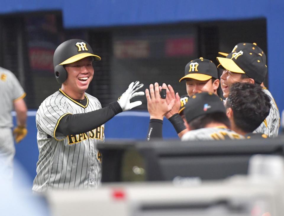 　６回、近本の適時三塁打で生還し、ナインの出迎えに笑顔で応える村上（撮影・立川洋一郎）