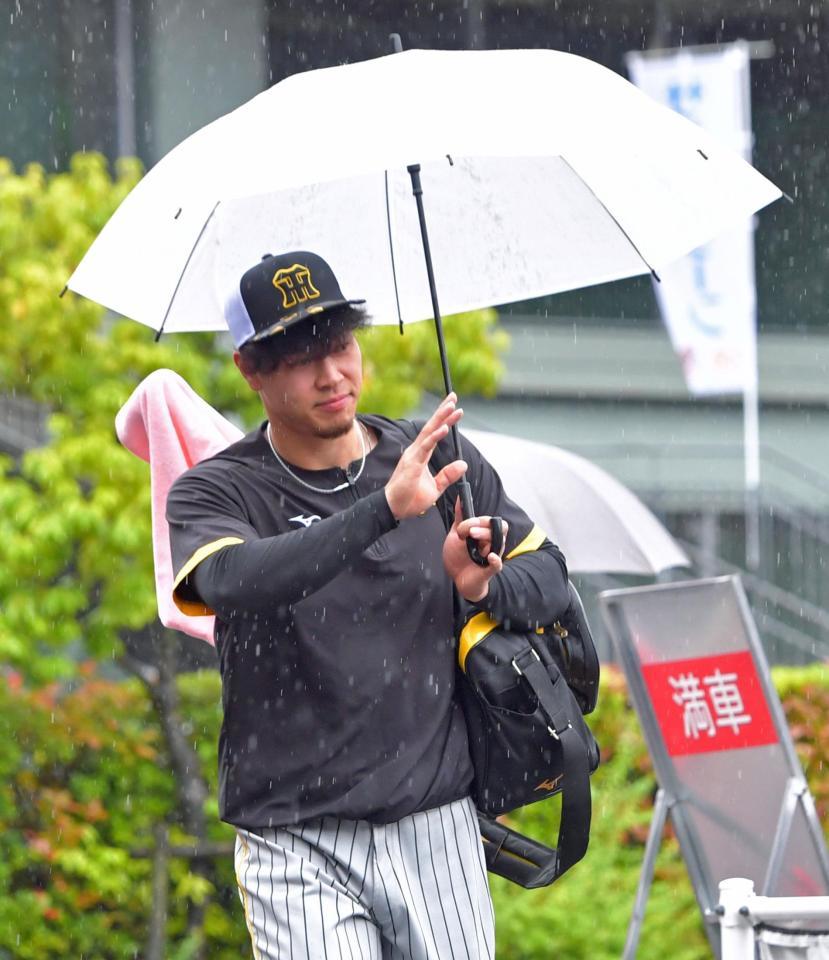 　雨の中、室内練習場へ向かう佐藤輝（撮影・立川洋一郎）