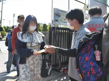 　スタッフから入場整理券を受け取るファン（左）＝一部加工しています（撮影・石井剣太郎）