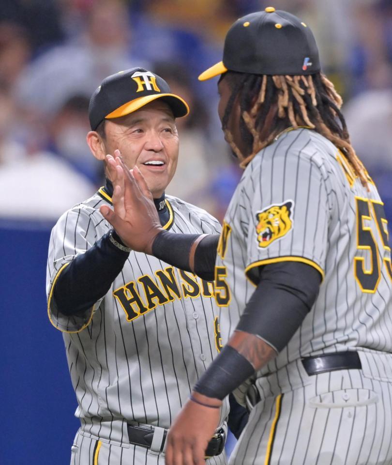 　７連勝で貯金を１０に伸ばし、ミエセス（右）とタッチを交わして笑顔を見せる岡田監督（撮影・立川洋一郎）